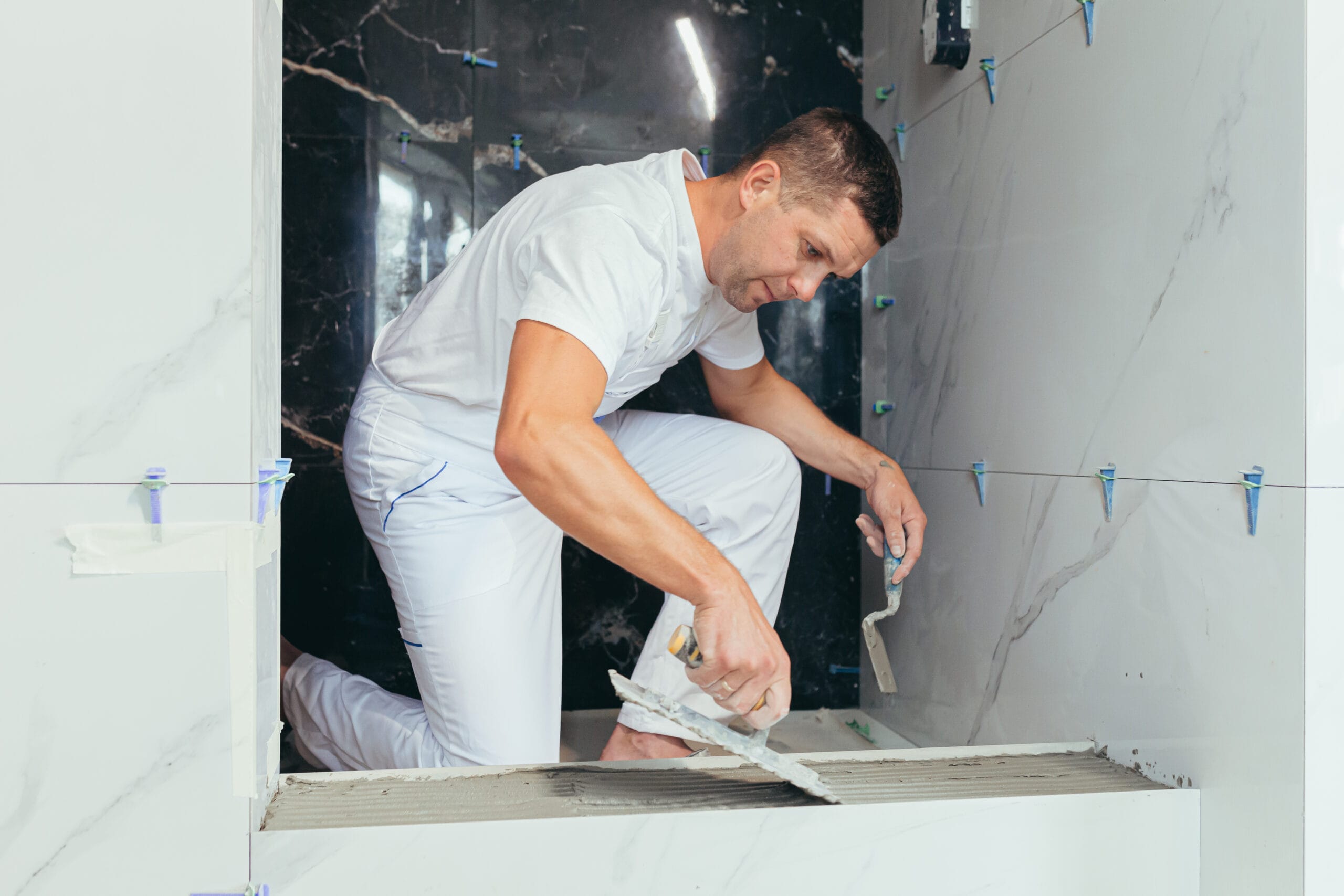 Male professional worker mounts ceramic tiles in the bathroom