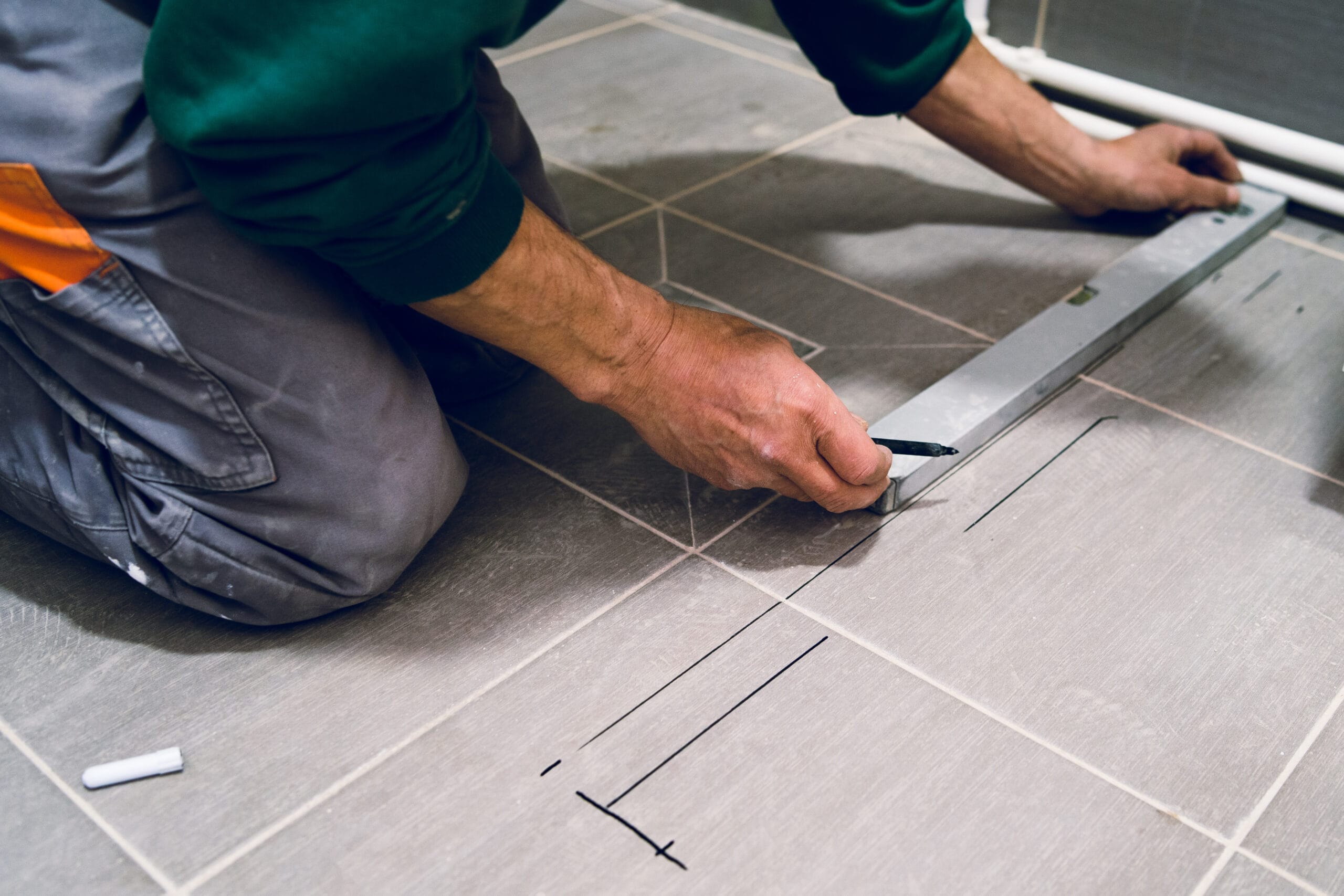 Construction worker craftsman measuring tiles on the floor before installation of the glass tile protective wall equipment rénovation Mérignac Gironde